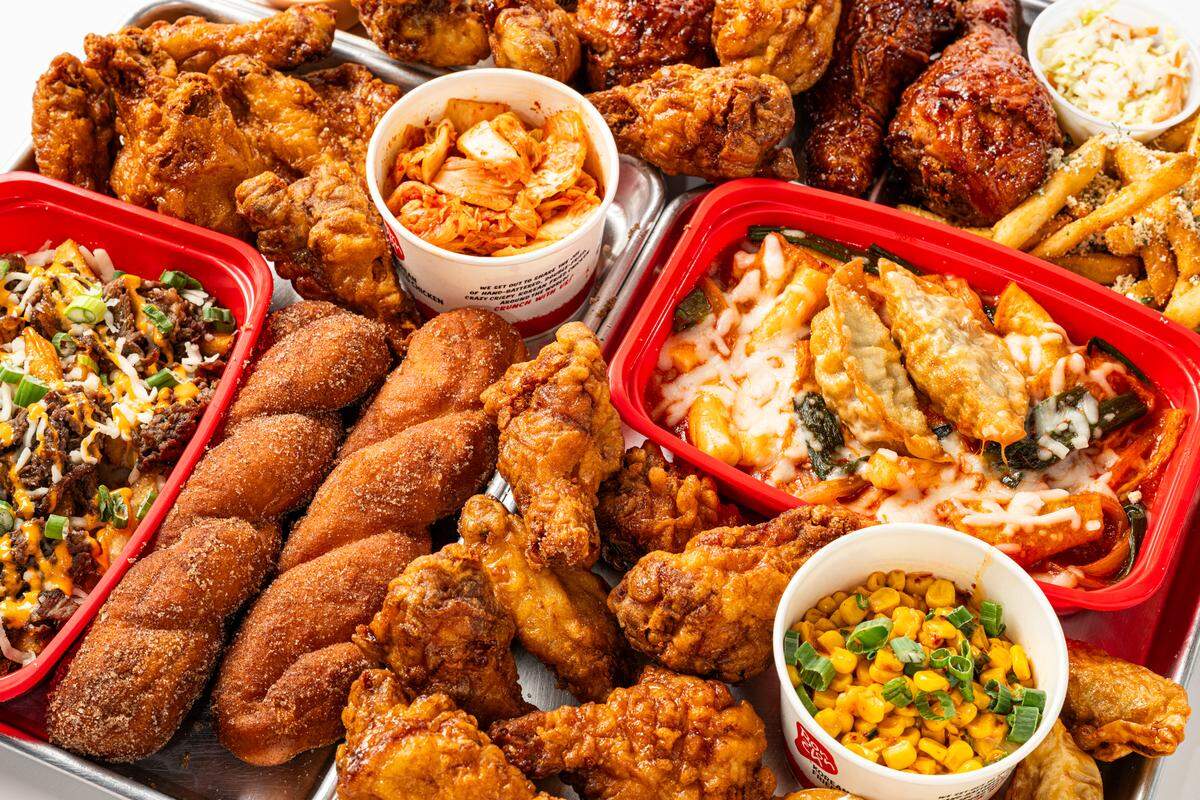 Un plato de pollo frito en Bonchon, que incluye acompañamientos como papas fritas, dumplings y kimchi.
