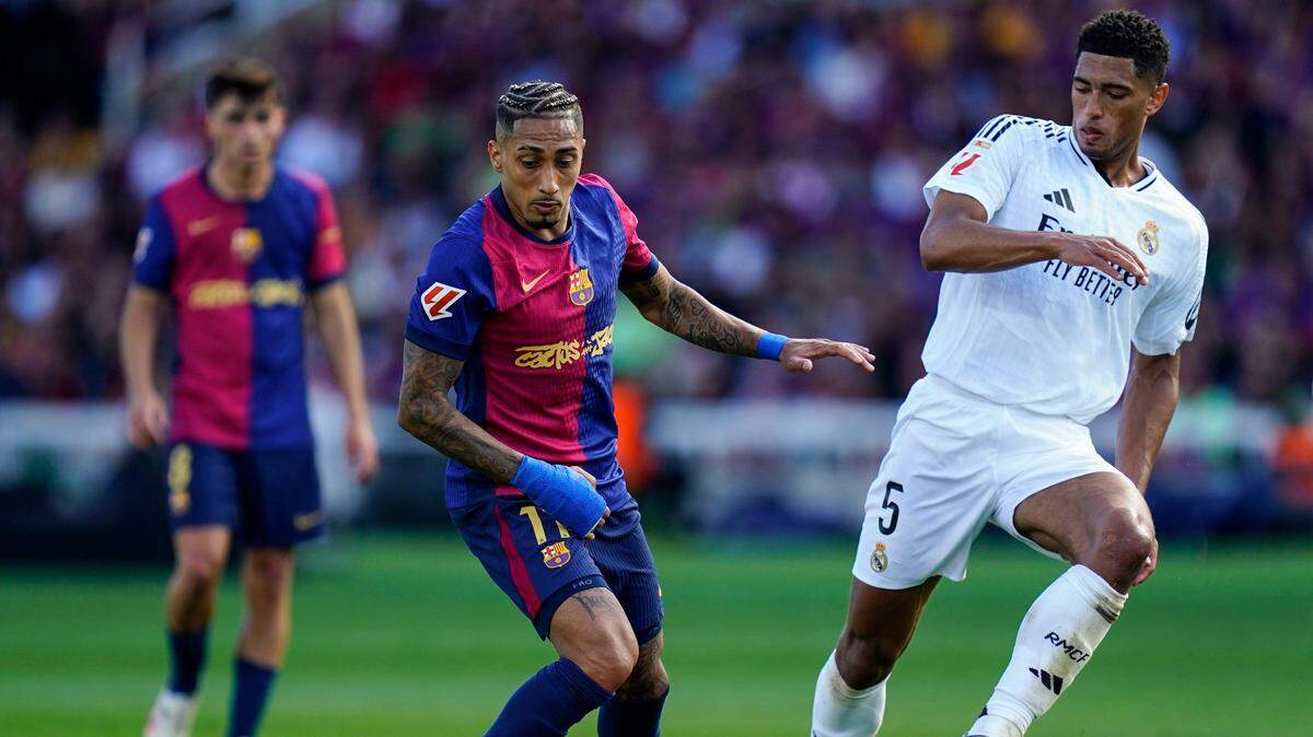 El jugador de Barcelona Raphinha (izq.) controla el balón ante Jude Bellingham, del Real Madrid, durante el partido de la liga española celebrado el 11 de mayo de 2025 en el Estadio Lluis Companys, en Barcelona. 