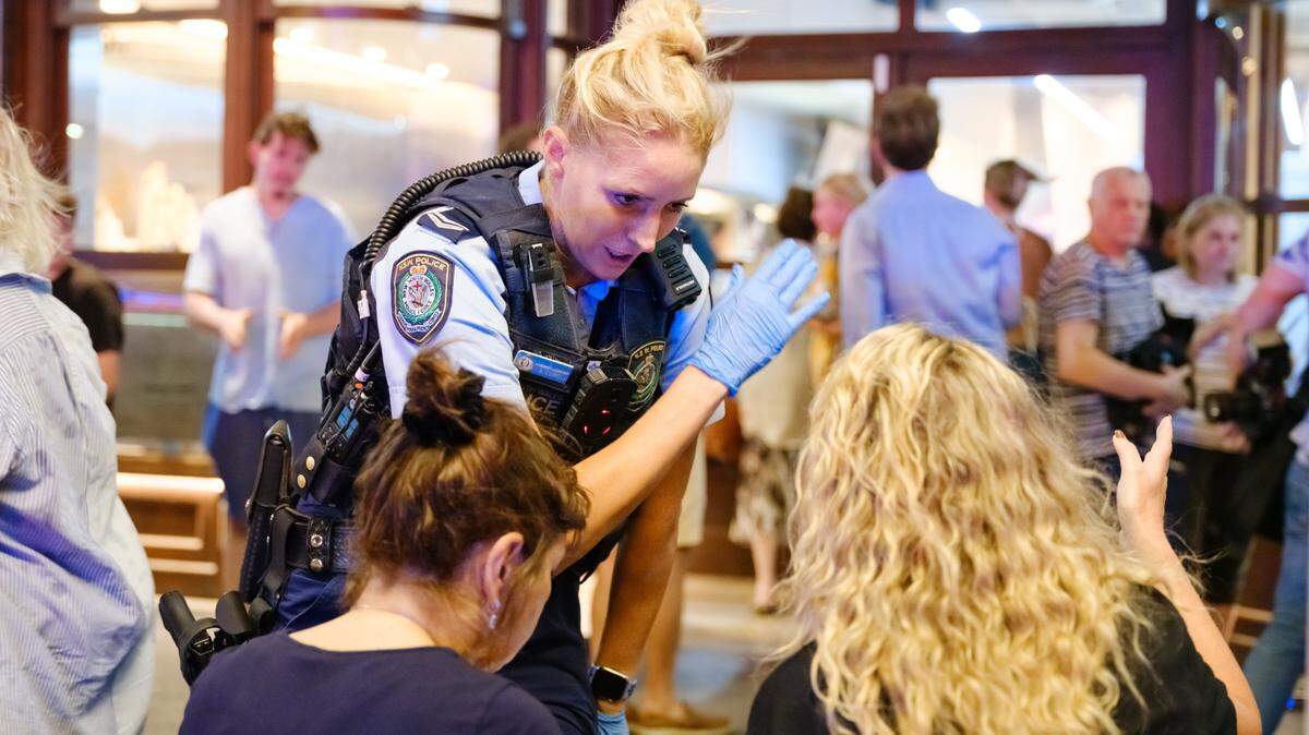 SYDNEY, AUSTRALIA - DECEMBER 14: Police first responders speak to members of the public at the scene of a mass shooting at Bondi Beach on December 14, 2025 in Sydney, Australia. Two gunmen dressed in black fired several shots at Sydney's world-famous Bondi Beach, causing at least 10 fatalities and several more casualties, as New South Wales police said the toll was very likely to climb. (Photo by George Chan/Getty Images)