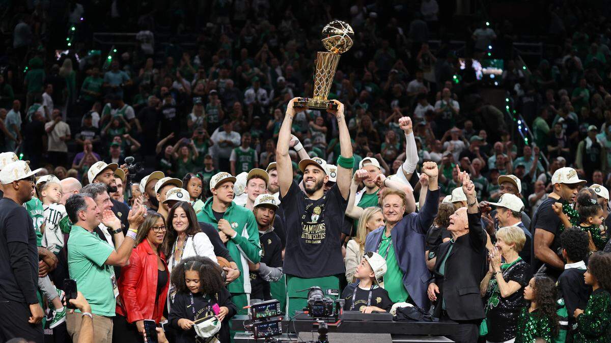 El jugador de los Celtics Jayson Tatum carga el trofeo que proclamó a su equipo como campeón de la NBA tras vencer en la final a los Mavericks de Dallas, el 17 de junio de 2024 en Boston.