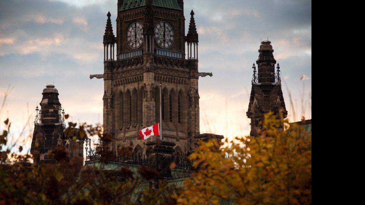 Una bandera al lado del edificio del Parlamento de Canadá