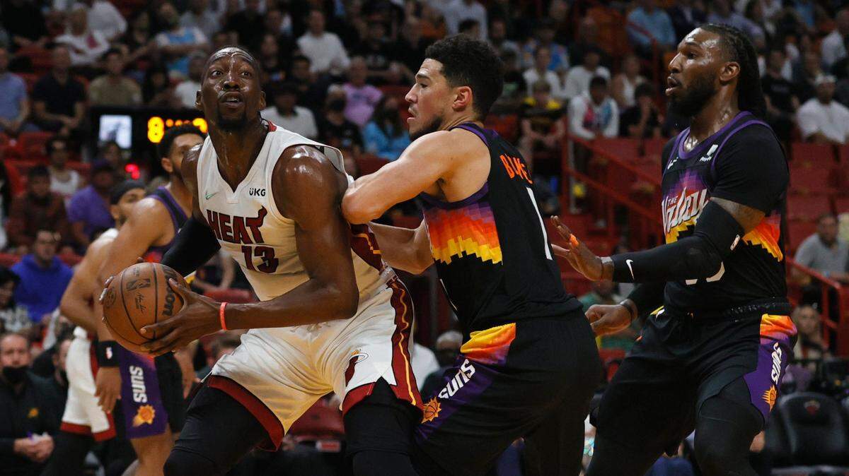 El jugador del Heat Bam Adebayo trata de anotar ante la marca de Devin Booker (centro) y Jae Crowder (der.) de los Suns de Phoenix, en el partido celebrado el 9 de marzo de 2022 en Miami.