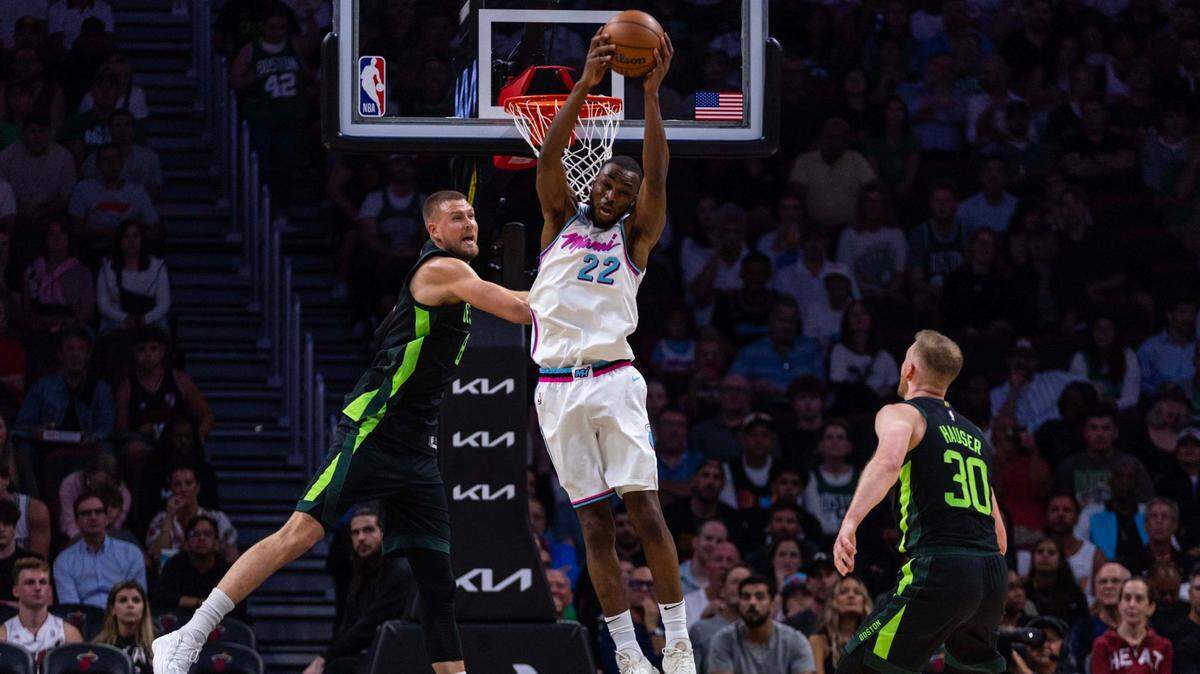 El delantero del Heat, Andrew Wiggins (22), toma un rebote contra el pívot de los Celtics de Boston, Kristaps Porzingis (izq.), durante la primera mitad del partido de la NBA celebrado el 10 de febrero de 2025 en el Kaseya Center, en Miami. 