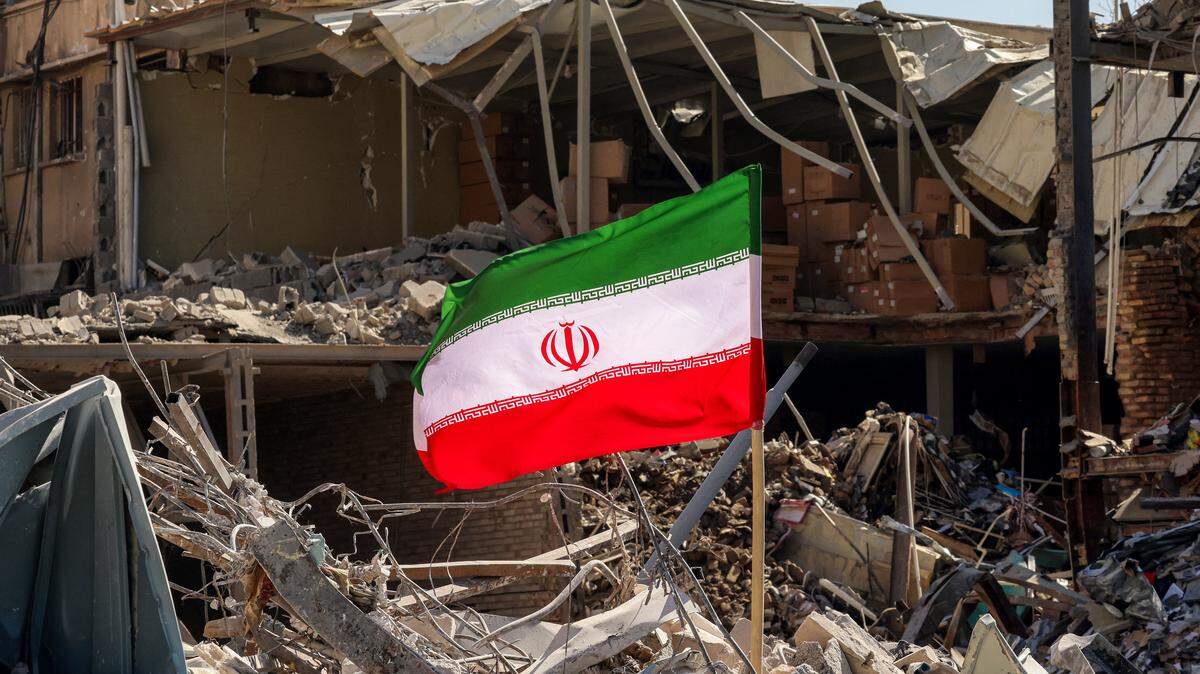 Una bandera iraní está colocada entre escombros y restos junto a un edificio residencial destruido cerca de la plaza Ferdowsi en Teherán el 3 de marzo de 2026.