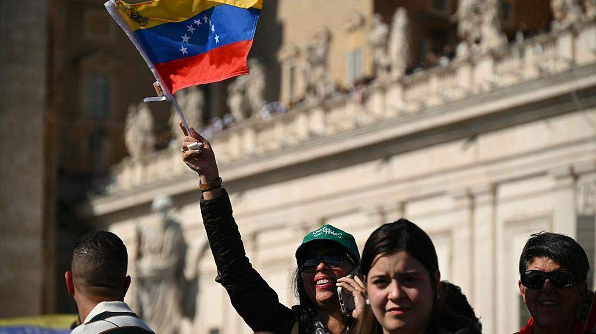 A woman waves a Venezuela's flags as faithful wait for Pope Leo XIV tour after a mass for the canonization of seven new Saints at St Peter's square in The Vatican, on October 19, 2025. (Photo by Filippo MONTEFORTE / AFP) (Photo by FILIPPO MONTEFORTE/AFP via Getty Images)