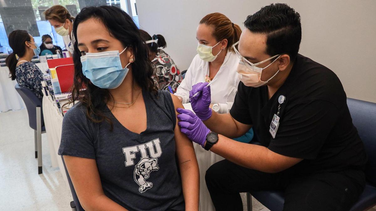 Camila Gutiérrez, estudiante de tercer año en la Universidad Internacional de Florida, a la izquierda, recibe su vacuna contra el COVID-19 de parte del estudiante de farmacia de la Universidad de Florida Jason Rodríguez, a la derecha, en el Centro de Rehabilitación Christine E. Lynn en Miami, Florida, el jueves 15 de abril de 2021.