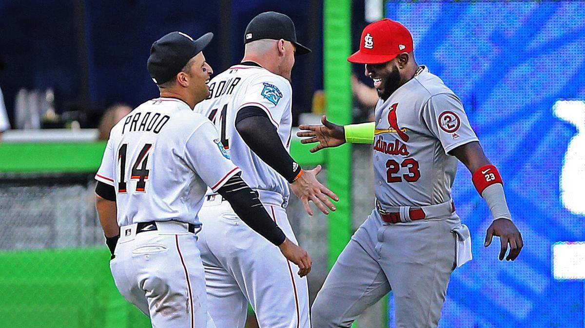 MARCELL OZUNA es saludado por Justin Bour y Martín Prado antes del inicio del juego del lunes contra los Cardenales en Miami.