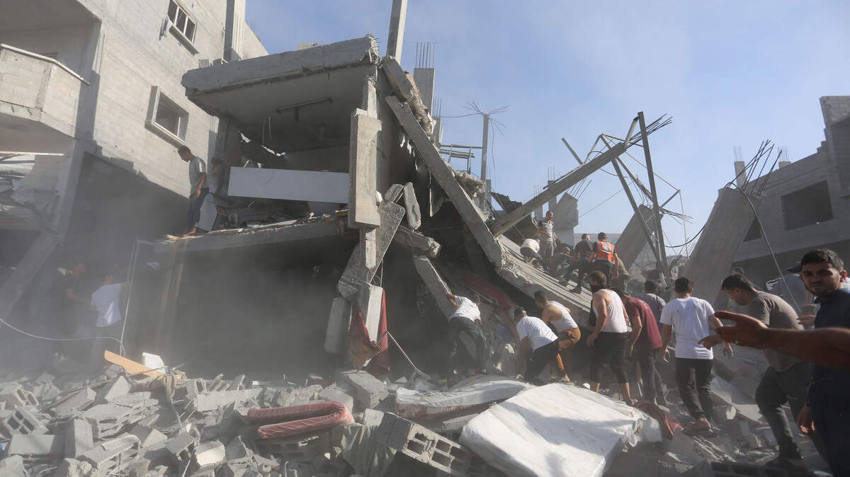 Una decena de personas revisa los escombros de un edificio destruido por un bombardeo israelí en busca de sobrevivientes, en la ciudad de Rafah, en la Franja de Gaza, el jueves 26 de octubre de 2023.