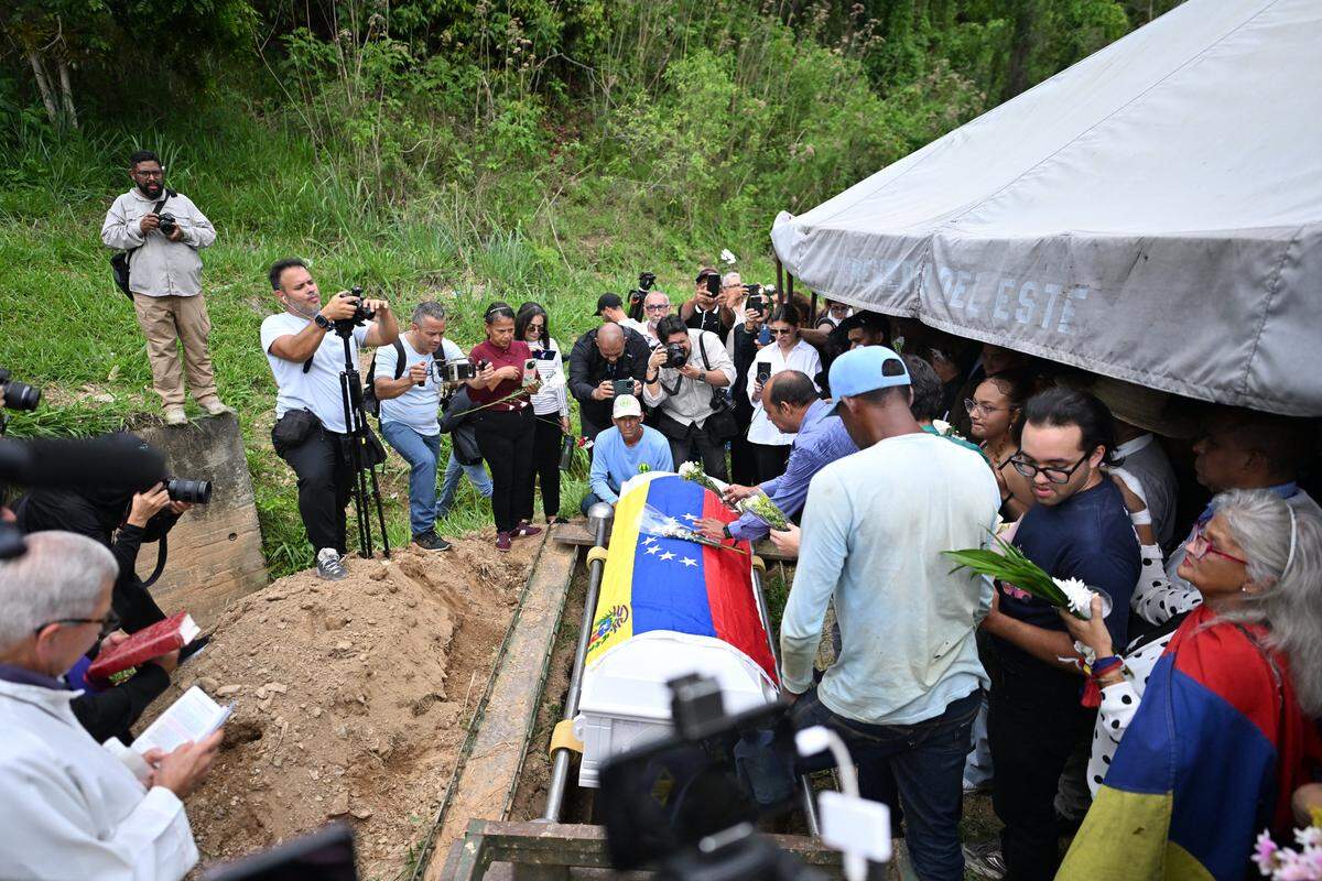 Relatives and members of the civil society surround the coffin of Carmen Navas, mother of late political prisoner Victor Quero Navas, during her burial in Caracas, on May 18, 2026. The mother of Venezuelan political prisoner Victor Hugo Quero Navas died on May 17, 2026 at age 81, just days after confirming the death of her son in state custody, her relatives told AFP. (Photo by Juan BARRETO / AFP via Getty Images)