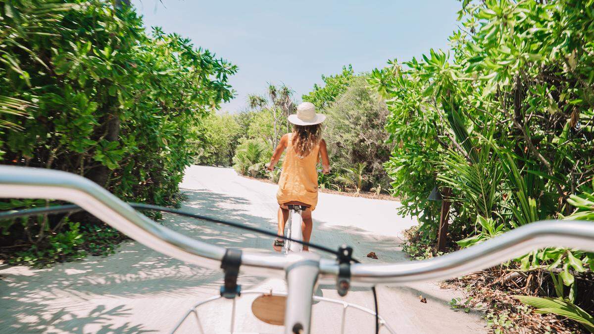 Pov point of view of couple cycling on tropical island. Personal perspective of person cycling with girlfriend in front. Tropical luxury vacations