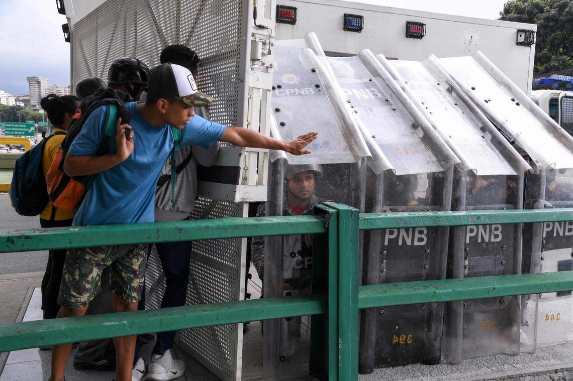 Miembros de la Policía Nacional Bolivariana permanecen detrás de una barrera colocada para bloquear una marcha convocada por estudiantes universitarios contra el gobierno del presidente venezolano Nicolás Maduro en Caracas