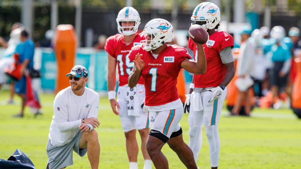 El quarterback de los Dolphins Tua Tagovailoa pasa el ovoide ante la mirada de sus compañeros Teddy Bridgewater (der.) y Skylar Thompson durante una práctica conjunta con los Eagles de Filadelfia, celebrada el 24 de agosto de 2022 en el Baptist Health Training Complex, en el Hard Rock Stadium de Miami Gardens, Florida.