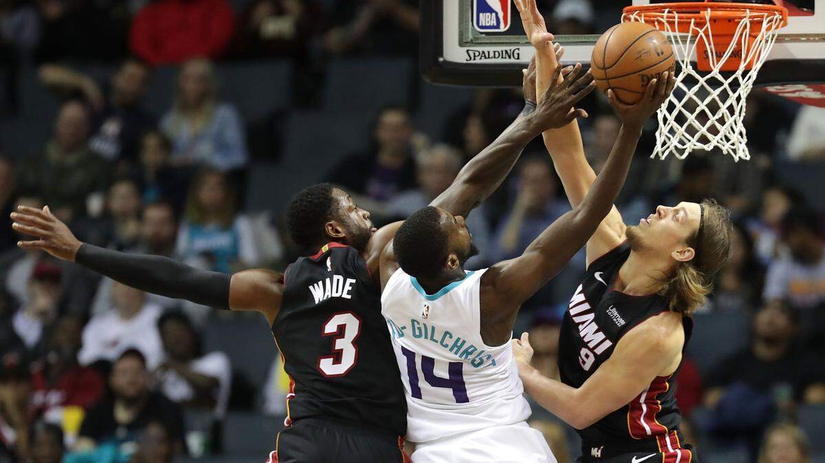 Los jugadores del Heat Dwayne Wade (#3) y Kelly Olynyk (#9) tratan de detener el tiro de Michael Kidd-Gilchrist, de los Hornets, en el partido efectuado el 30 de octubre de 2018 en Charlotte.