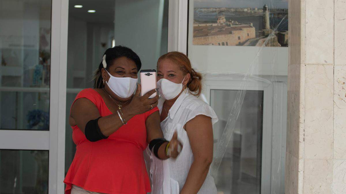 Women make a video call using a pre-paid, public wifi connection near a park that’s popular for connectivity in downtown Havana, Cuba, Tuesday, July 14, 2021, amid the COVID-19 pandemic. (AP Photo/Eliana Aponte)