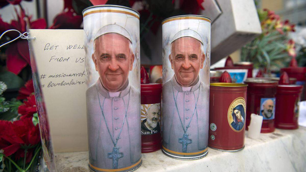 Velas con la foto del papa Francisco fueron colocadas debajo de una estatua del papa Juan Pablo II, que está al frente de la Clínica Agostino Gemelli en donde está hospitalizado el Santo Padre, en Roma, el miércoles 19 de febrero de 2025.
