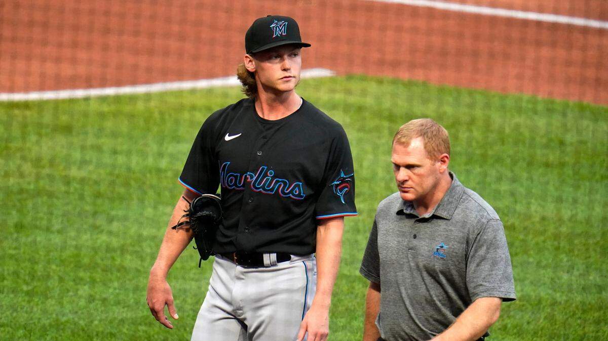 El abridor de los Marlins, Max Meyer, sale del campo con un entrenador del equipo después de hacer 10 lanzamientos en la primera entrada durante el partido contra los Piratas, el 23 de julio de 2022 en Pittsburgh.