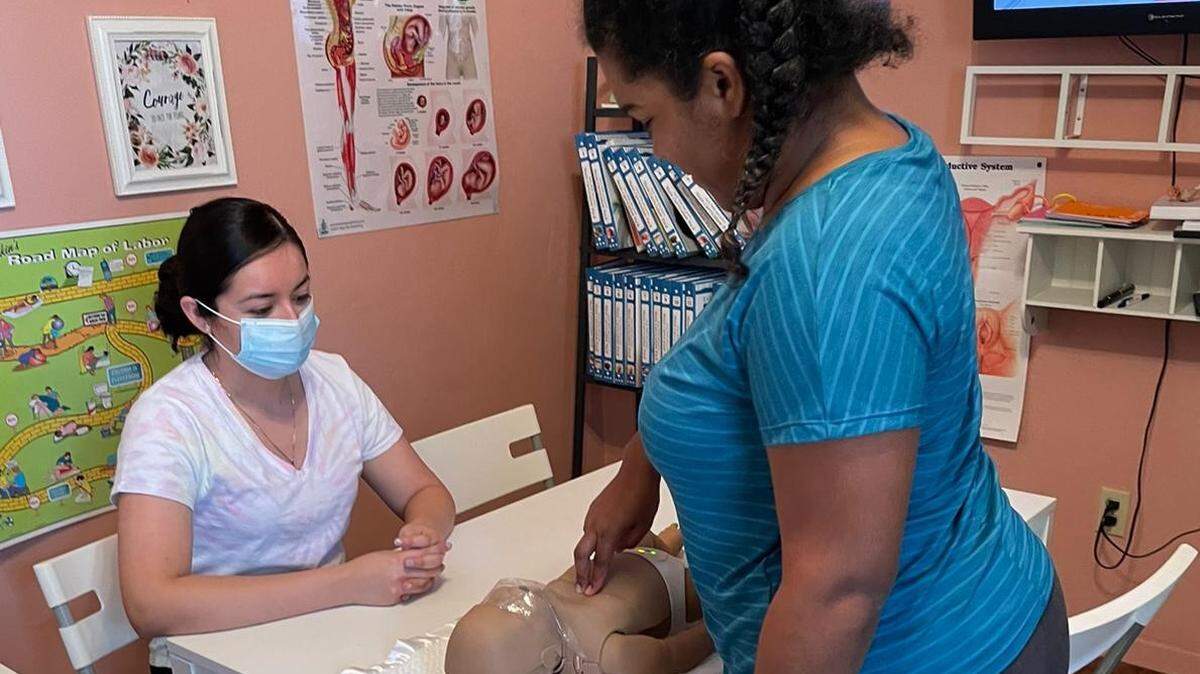 Stephanie García y Octaviana Pacheco practican con un muñeco sobre cómo dar clases sobre el cuidado del bebé en Tree of Life Parentig Center, organización sin fines de lucro