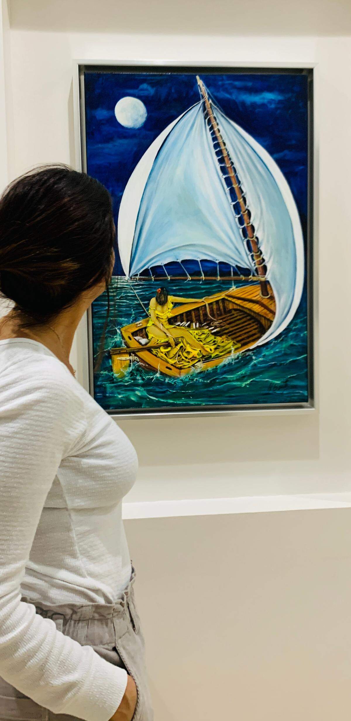 Janet Díaz Bonilla observa el cuadro del pintor cubano Humberto Benítez, que se refleja en la etiqueta de La Marielita Rum. ‘Quería celebrar a la virgen de la Caridad, de la que soy muy devota’, explica Díaz Bonilla, sobre por qué está vestida de amarillo en su travesía por mar desde Cuba.