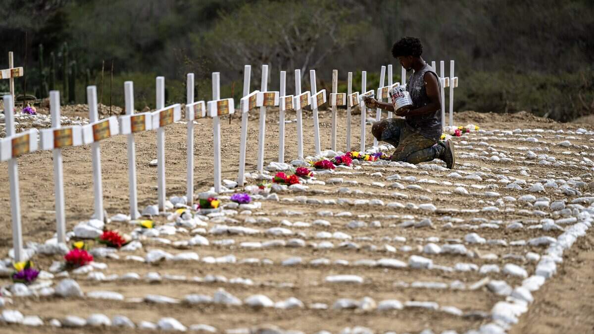 A worker paints graves for unidentified victims of the June 24 earthquake at La Esperanza Cemetery in Catia La Mar, La Guaira state, northeast of Caracas, on July 5, 2026. Venezuela's devastating twin earthquakes killed nearly 3,000, updated official figures showed on July 4, as international rescue teams began winding down search operations for survivors in the rubble of the disaster. (Photo by Miguel MEDINA / AFP via Getty Images)