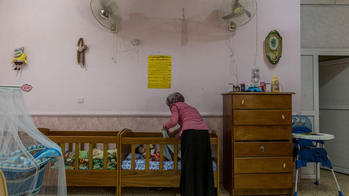 Miles de niños han perdido a sus padres bajo la brutalidad del Estado Islámico y las prolongadas batallas para arrebatar territorio iraquí de su dominio. En la foto, una mujer echa una manta sobre un niño que acaba de llegar al orfanatorio.