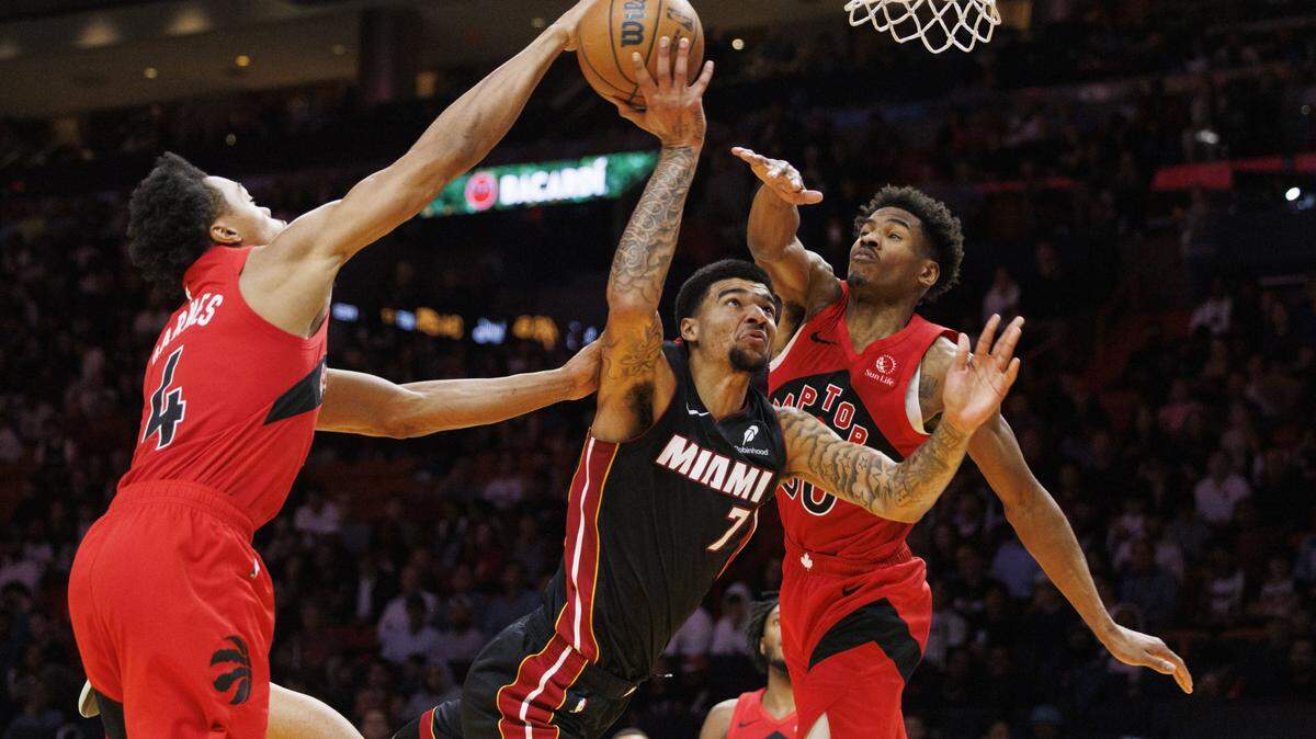 El pívot de los Heat, Kel’El Ware (7), es bloqueado por el alero, Scottie Barnes (4), y el escolta Ochai Agbaji (30), de los Raptors de Toronto, durante la segunda mitad de un partido disputado el 15 de diciembre de 2025 en el Kaseys Center, en Miami. 