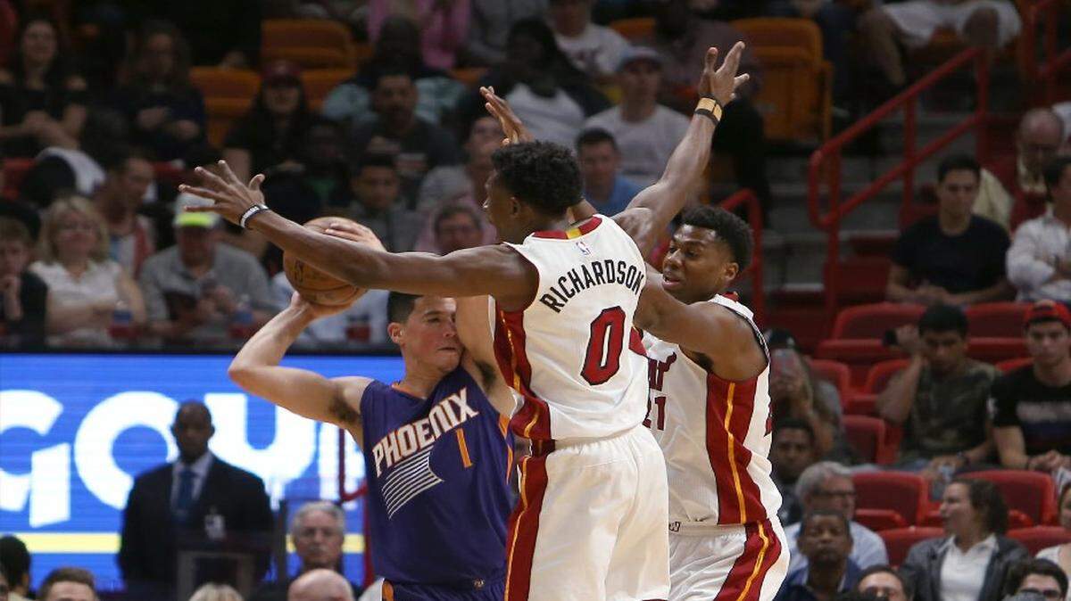 El jugador de Phoenix Devin Booker (izq.) trata de pasar la pelota ante la marca de Josh Richardson (0) y Hassan Whiteside, del Heat, en el primer cuarto del partido efectuado el 21 de marzo del 2017 en Miami.