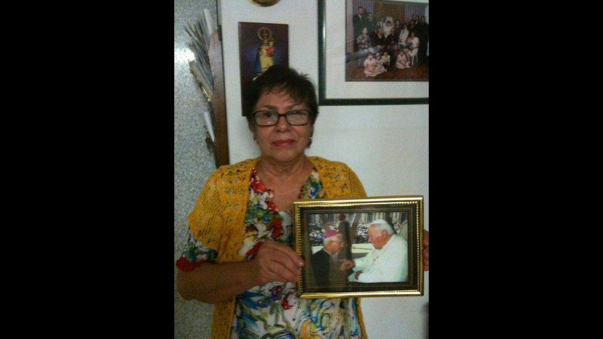Iraida Román Martínez at her Little Havana home in 2012, holding a photo of her brother, Monsignor Agustín Román, with Pope John Paul II.