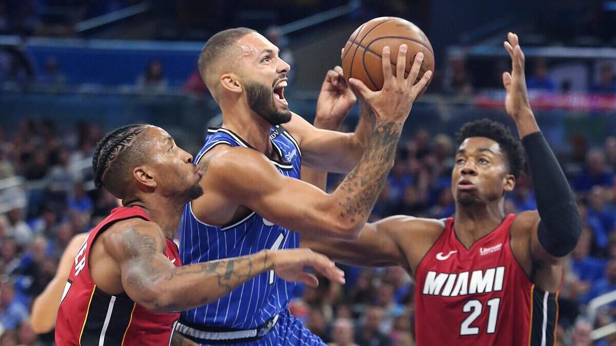 El jugador del Magic Evan Fournier (centro) entra al aro ante la marca de Rodney McGruder (izq.) y Hassan Whiteside, del Heat, en el partido celebrado el 17 de octubre de 2018 en Orlando.