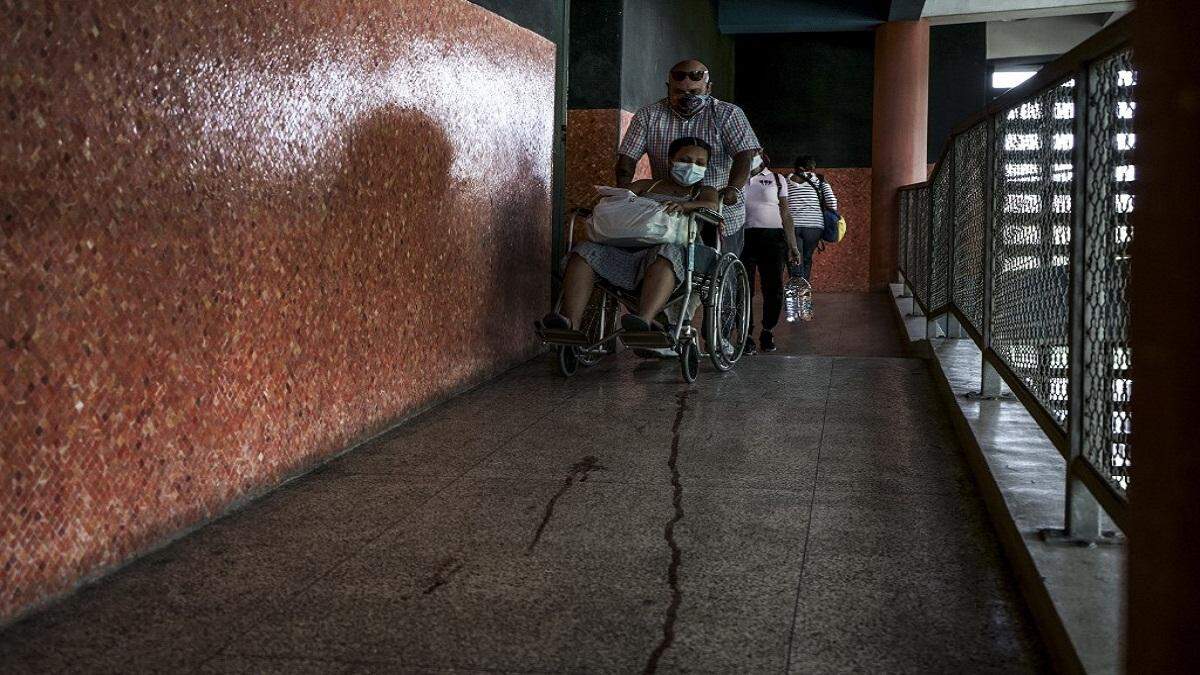 Briggite Pérez es conducida en silla de ruedas por su padre al salir del Hospital Universitario luego de ser operada por una infección en la cesárea que se le practicó por el nacimiento de su bebé en Caracas el 9 de enero de 2021.
