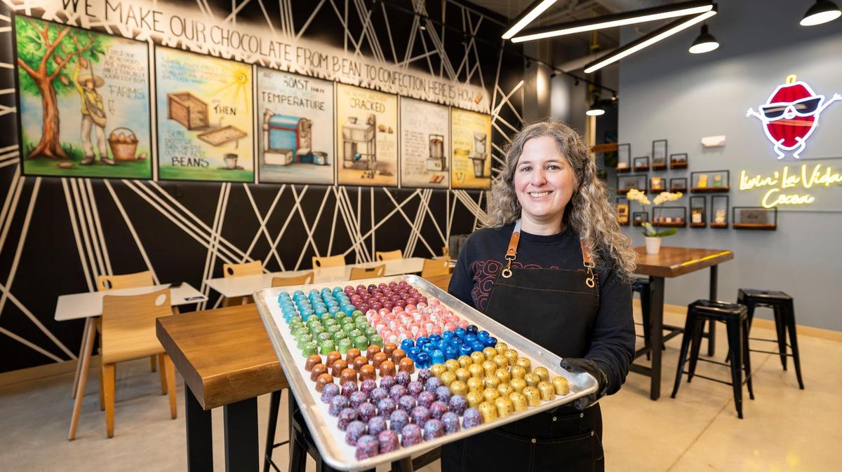 Carolina Quijano, fundadora de Exquisito Chocolates, sostiene una bandeja de bombones surtidos dentro de su nueva fábrica en la Calle Ocho.