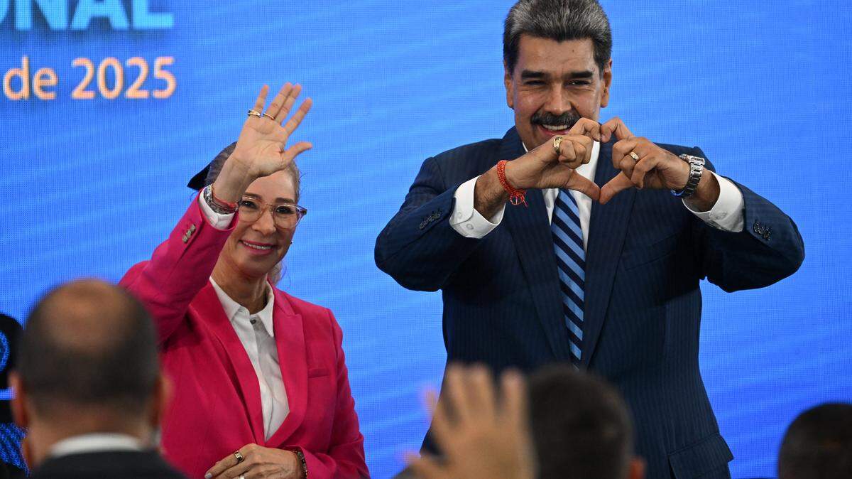 Venezuela's President Nicolas Maduro (R) makes a heart shape with his hands next to First Lady Cilia Flores during the Meeting of Jurists in Defense of International Law at the Eurobuilding Hotel in Caracas on November 14, 2025. (Photo by Federico PARRA / AFP) (Photo by FEDERICO PARRA/AFP via Getty Images)