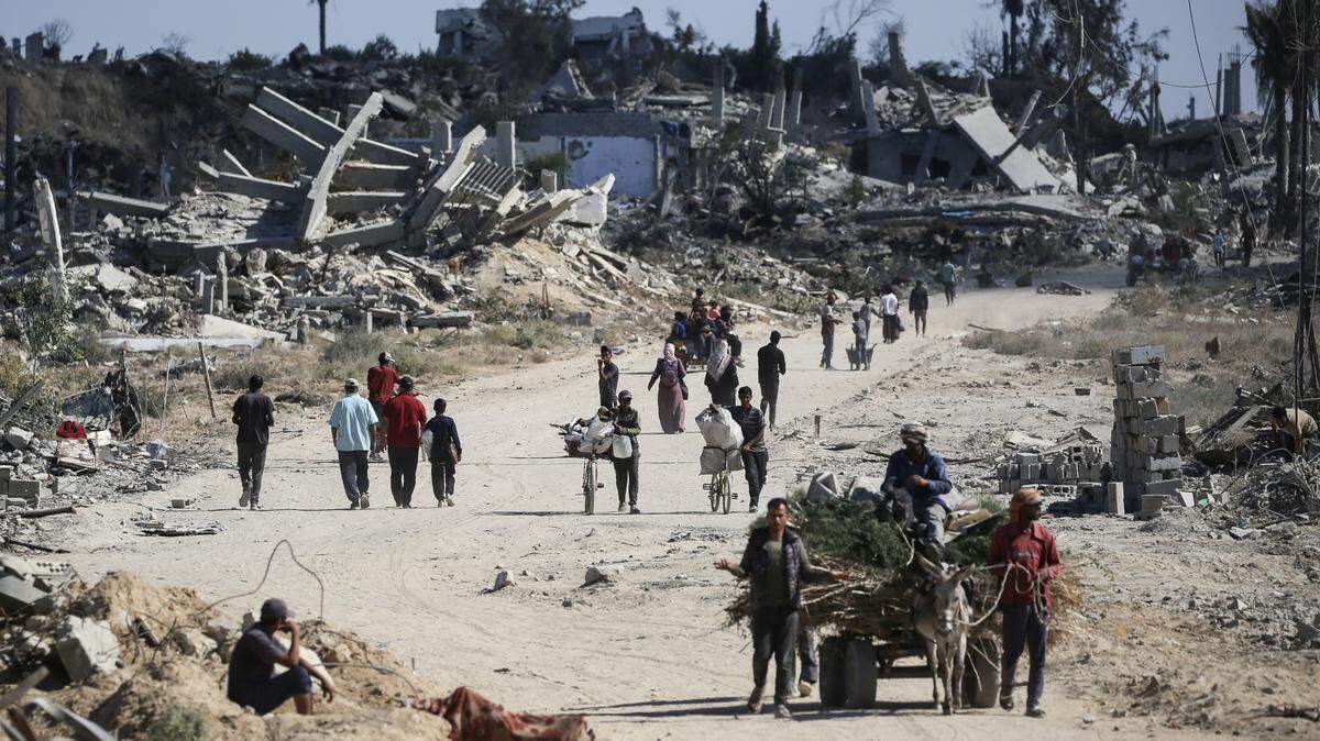 Displaced Palestinians walk past destroyed buildings as they return to their homes in the in al-Zahra area, north of the Nuseirat refugee camp in the central Gaza Strip, on October 14, 2025, a day after a ceasefire came into effect. The US president hailed a "tremendous day for the Middle East" as he and regional leaders signed a declaration on October 13, 2025 meant to cement a ceasefire in Gaza, hours after Israel and Hamas exchanged hostages and prisoners. (Photo by Eyad BABA / AFP) (Photo by EYAD BABA/AFP via Getty Images)