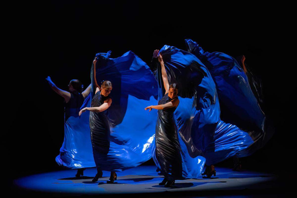 Las mujeres del Ballet Flamenco Sara Baras levantan en vuelo unas voluminosas sayas de azul butano, la extraña tela futurística flotando alrededor de ellas como enormes olas en el mar. 
