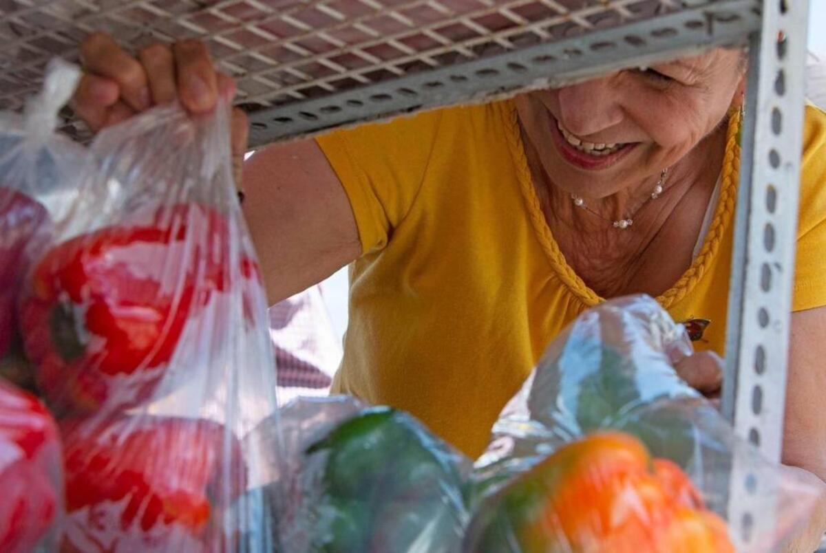 Delia Rodríguez escoje vegetales entre la variedad de productos disponibles en el camión de Arturo Tamayo en Miami.