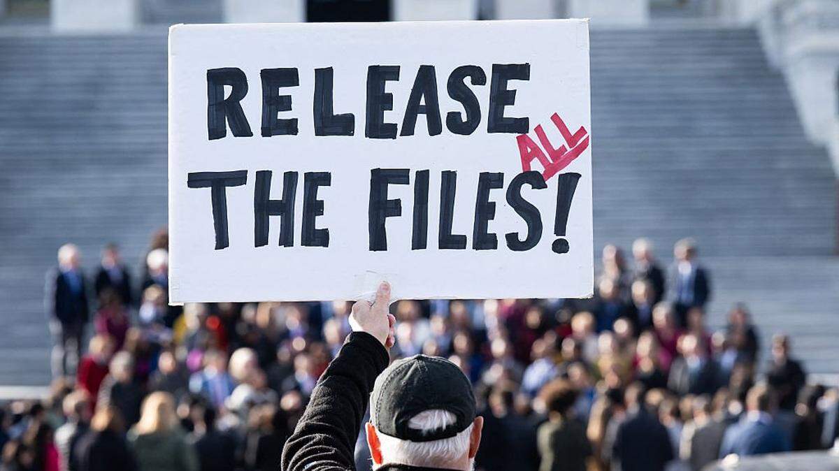 TOPSHOT - A protester holds a sign related to the release of the Jeffrey Epstein case files outside the US Capitol in Washington, DC, November 12, 2025. Democrats released emails Wednesday in which Jeffrey Epstein suggested Donald Trump was aware of the disgraced financier's sexual abuse and had "spent hours" with one of his victims at his house. Trump has denied any knowledge of the sex-trafficking activities of his former friend, who died by suicide in 2019 as he was in prison awaiting trial, and the White House accused Democrats of pushing a "fake narrative" by sharing the mails. (Photo by SAUL LOEB / AFP) (Photo by SAUL LOEB/AFP via Getty Images)