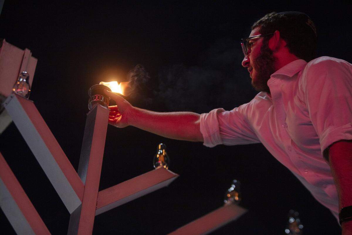 Yossi Spivak, de 17 años, enciende la primera vela durante el gran encendido de la menorá que marca la primera noche de Januká en Lincoln Road, el 14 de diciembre de 2025, en Miami Beach, Florida. El encendido de la menorá y el festival de Januká marcaron el inicio de la festividad.