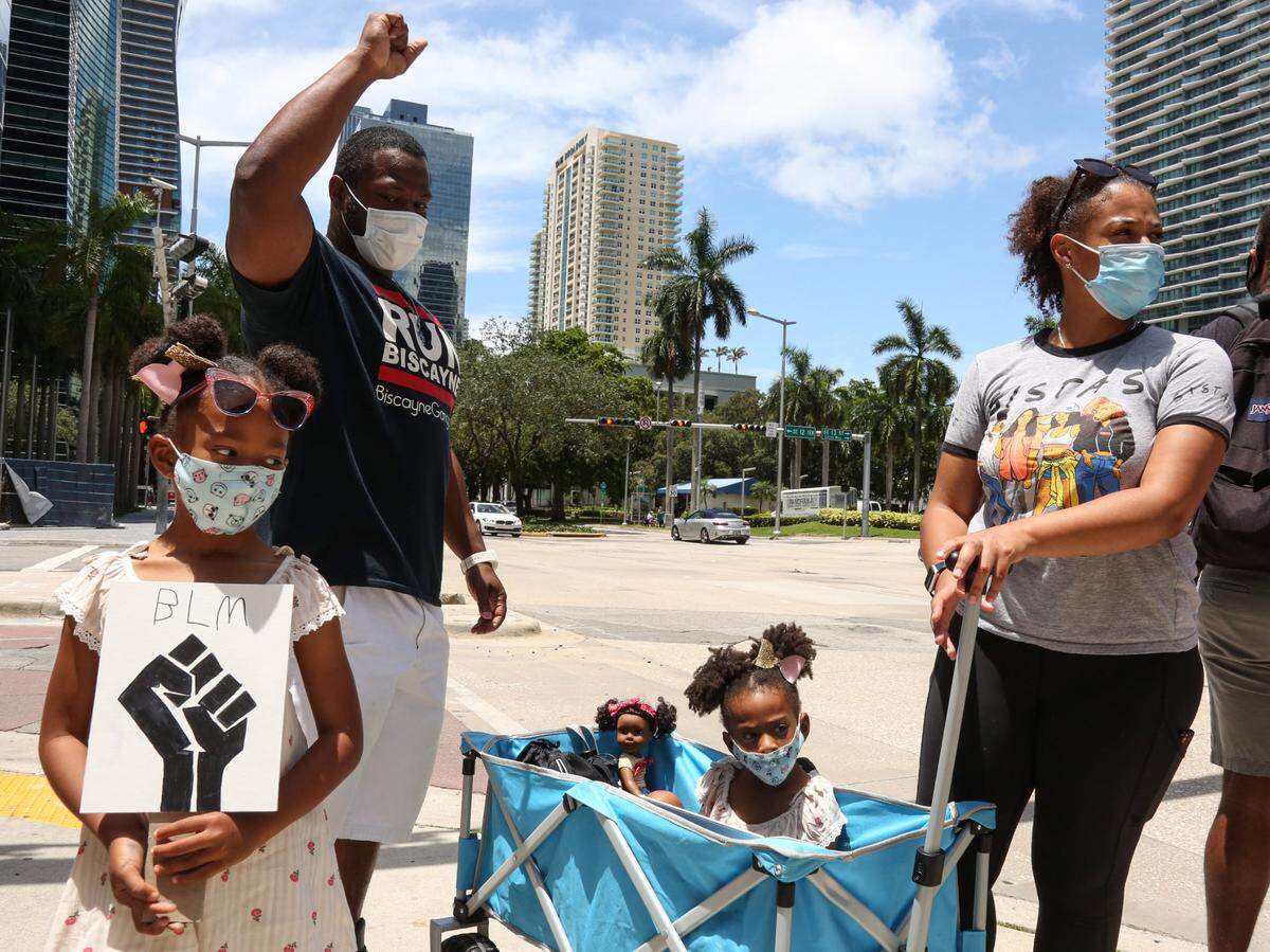 Ashley Hurst, derecha, y Rickman Johnson, alzando el puño, con sus dos hijas, Destiny, al frente, y Desiree, al centro, son vistos en una protesta en el vecindario de Brickell en Miami, el sábado 13 de junio de 2020.