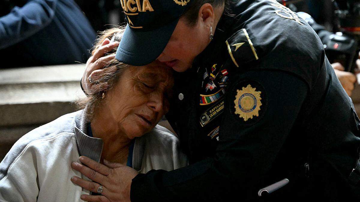Una agente de policía consuela a un familiar de un agente fallecido durante el funeral en la sede del Ministerio del Interior en Ciudad de Guatemala, el lunes 19 de julio de 2026. El presidente de Guatemala declaró el domingo el estado de emergencia en todo el país durante 30 días para combatir a las bandas criminales, después de que las autoridades acusaran a estos grupos de asesinar a nueve agentes de policía y de tomar rehenes en tres prisiones.
