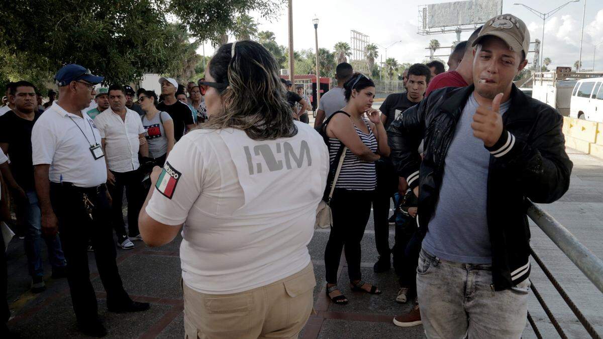 Ronald Sicilia Espinosa, a Cuban migrant, right, gives the thumbs up to well-wishers after being the first number called to cross into the United States to ask for asylum. Sicilia was happy that his turn finally came. after he had waited over two months for his number to be calle.