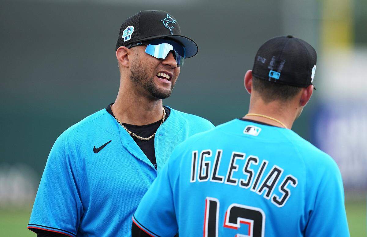 El bateador designado de los Marlins Yuli Gurriel (izq.) conversa con el torpedero José Iglesias antes del partido de pretemporada ante los Mets de New York, celebrado el 13 de marzo de 2023 en Jupiter, Florida.