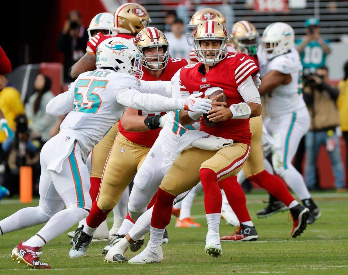 El quarterback de los 49ers de San Francisco Jimmy Garoppolo (10) es derribado por el linebacker de los Dolphins de Miami Jerome Baker (55) y el linebacker Jaelan Phillips (15), en el primer cuarto del partido celebrado el 4 de diciembre de 2022 en Santa Clara, California.