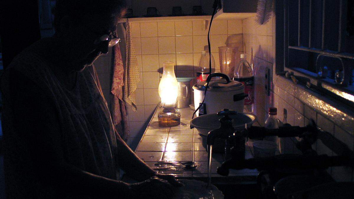 Una mujer lava los platos iluminada por una lámpara de queroseno en el habanero barrio de El Vedado. EFE/Alejandro Ernesto