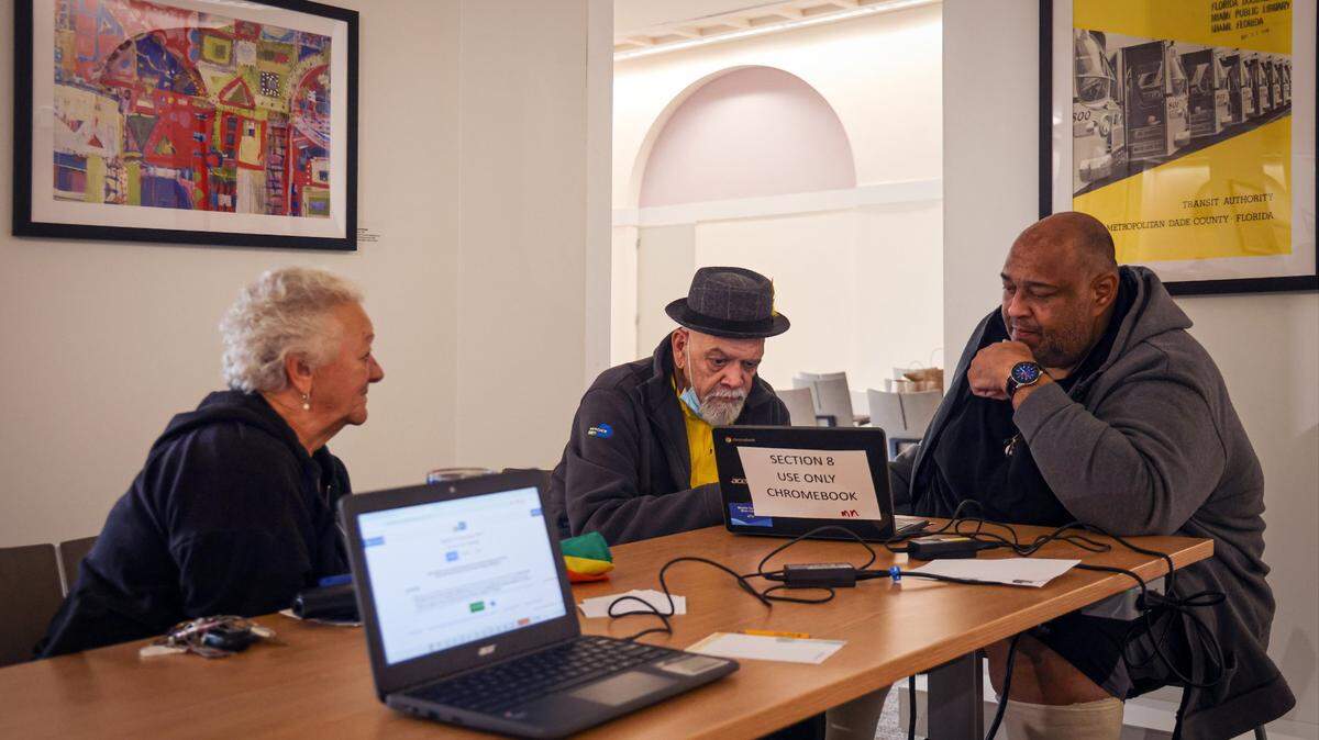 El bibliotecario Richard Cortina (centro) ayuda a Jesús Sánchez (der.) a hacer la solicitud para la lista del Plan 8, mientras Grace González espera, el 5 de febrero, en la Biblioteca principal de Miami-Dade en el downtown. El plazo para aplicar para la lista espera del Plan 8 se vence el 19 de febrero.