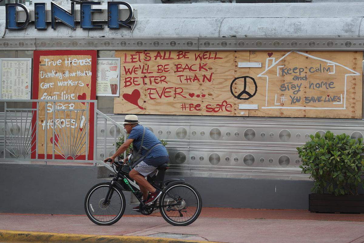 A bicyclist passes a restaurant with positive message about dealing with the coronavirus pandemic written on it on May 10, 2020 in Miami Beach, Florida.