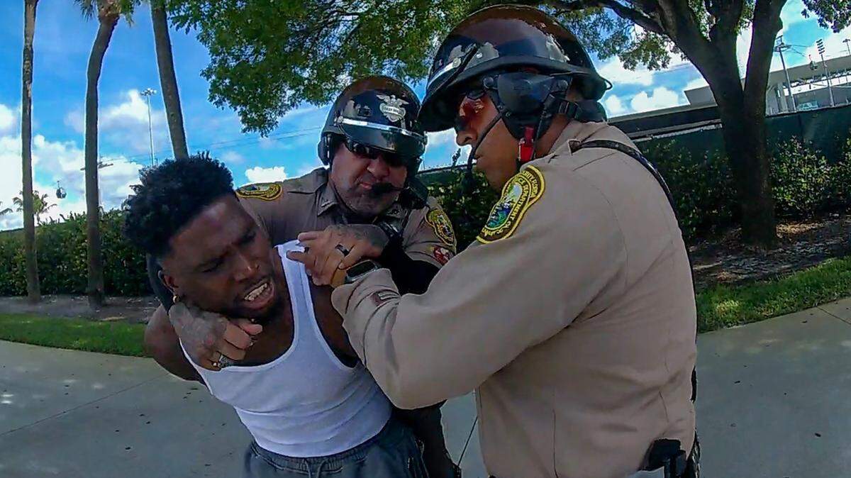 El oficial de policía de Miami-Dade, Danny Torres (izq), rodea con su brazo el cuello del jugador estrella de los Miami Dolphins, Tyreek Hill, en esta captura de fotografía de la grabación de la cámara corporal de la policía de Miami-Dade de la controvertida parada de tráfico de Hill, el domingo 8 de septiembre de 2024, cerca del Hard Rock Stadium.