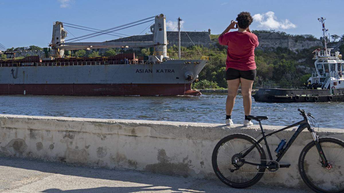 Una mujer toma fotografías del Asian Katra, un buque mercante con bandera panameña, mientras llega a la bahía de La Habana transportando ayuda humanitaria, en La Habana, Cuba, el 18 de mayo de 2026.