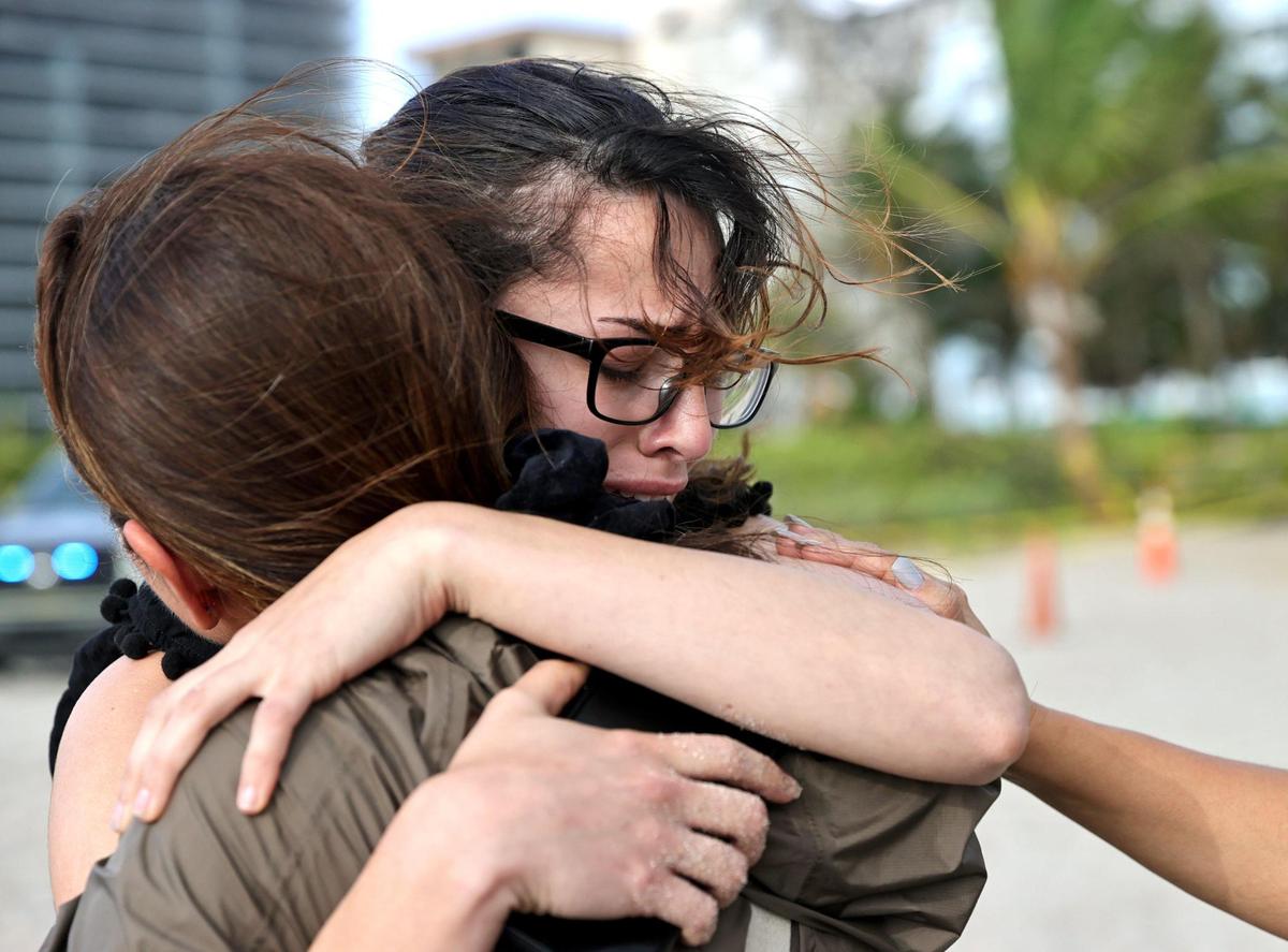 Fayzah Bushnaq (izq.) y Maria Fernanda Martinez se consuelan en el exterior de la torre de condominios Champlain Towers South en Surfside, Florida, el viernes 25 de junio. Familiares y amigos de los desaparecidos viven momentos de agonía mientras esperan.