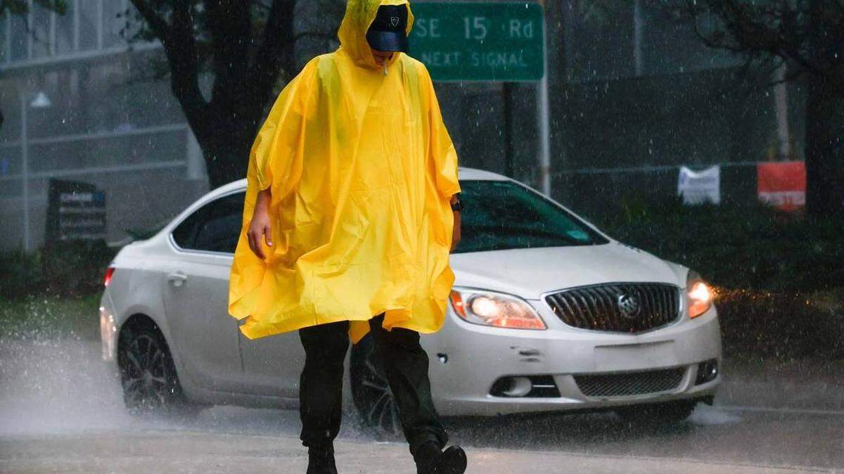 Un transeúnte con un poncho, camina bajo la lluvia en Brickell Avenue en Miami, Florida, el martes 27 de septiembre de 2022.