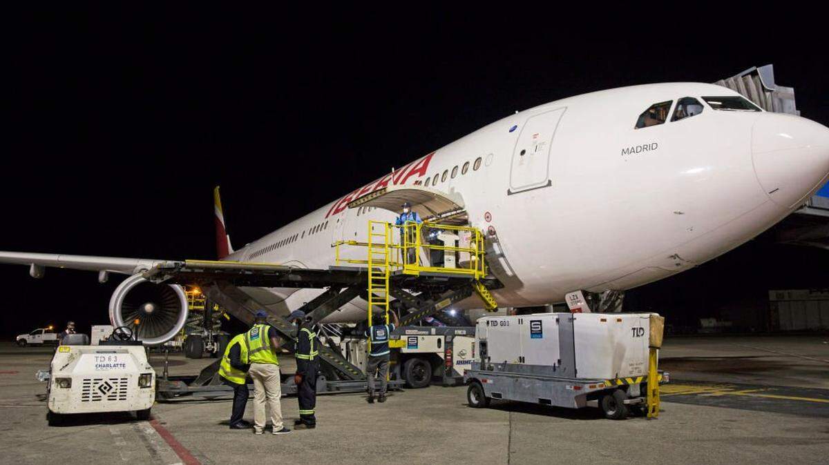 Airport workers prepare to unload shipping containers with Covishield vaccine doses, at the Las Americas International Airport in Santo Domingo, on February 15, 2021. - The shipment includes 110 kilos of the vaccine manufactured by a laboratory in India and under the license of AstraZeneca, which develops it together with the University of Oxford. (Photo by Erika SANTELICES / AFP) (Photo by ERIKA SANTELICES/afp/AFP via Getty Images)