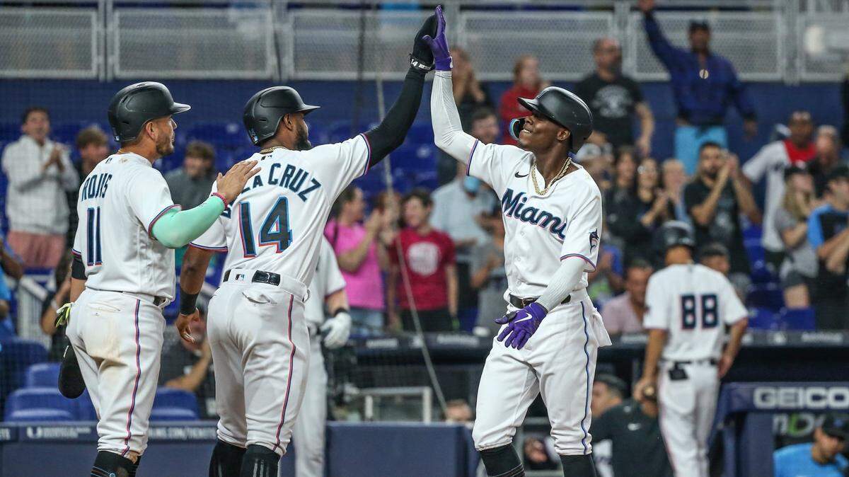 El segunda base de los Marlins Jazz Chisholm Jr. (der.) celebra en home con Miguel Rojas (izq.) y Bryan de la Cruz tras pegar un jonrón en el segundo inning del partido ante los Nacionales de Washington, celebrado el 7 de junio de 2022 en Miami.